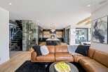 Experience modern luxury in this open-concept living space, featuring a stunning glass-encased wine cellar and a sleek, contemporary kitchen with a large island.
