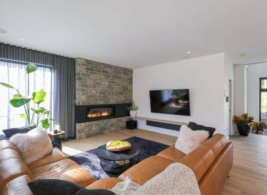 Experience modern luxury in this stunning living room, featuring a sleek gas fireplace set against a rustic stone accent wall.