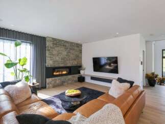 Experience modern luxury in this stunning living room, featuring a sleek gas fireplace set against a rustic stone accent wall.