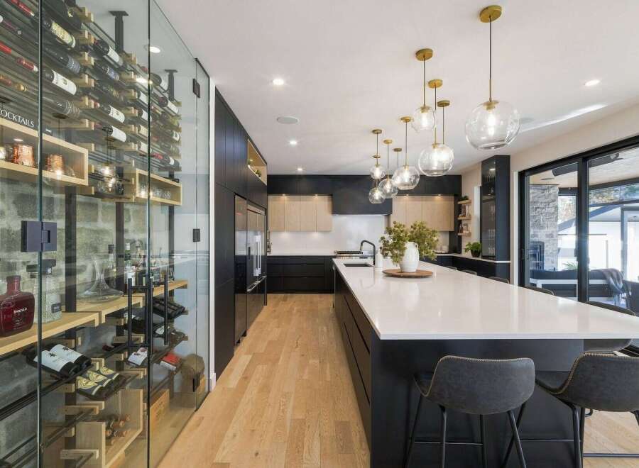 Experience luxury living in this stunning modern kitchen, featuring a state-of-the-art glass-enclosed wine cellar stocked with a wide selection of bottles.
