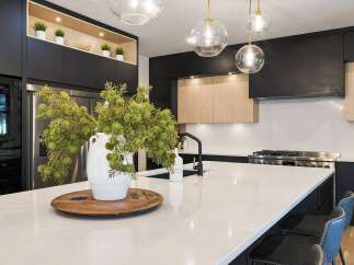 Experience luxury in this modern kitchen, featuring sleek black cabinetry and warm wood accents.