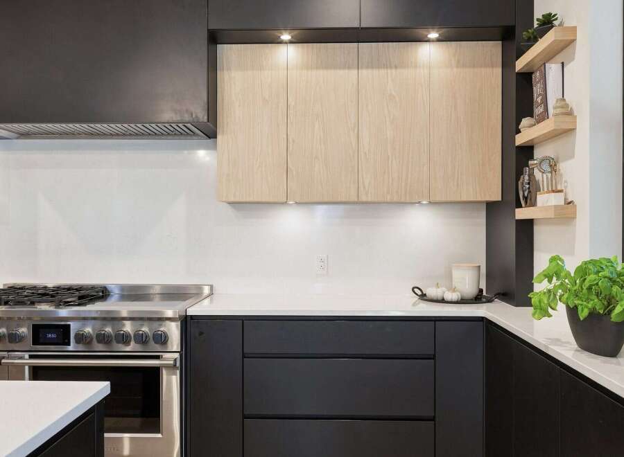 Experience modern luxury in this stunning kitchen, featuring sleek black cabinetry contrasted with warm, natural wood upper cabinets.