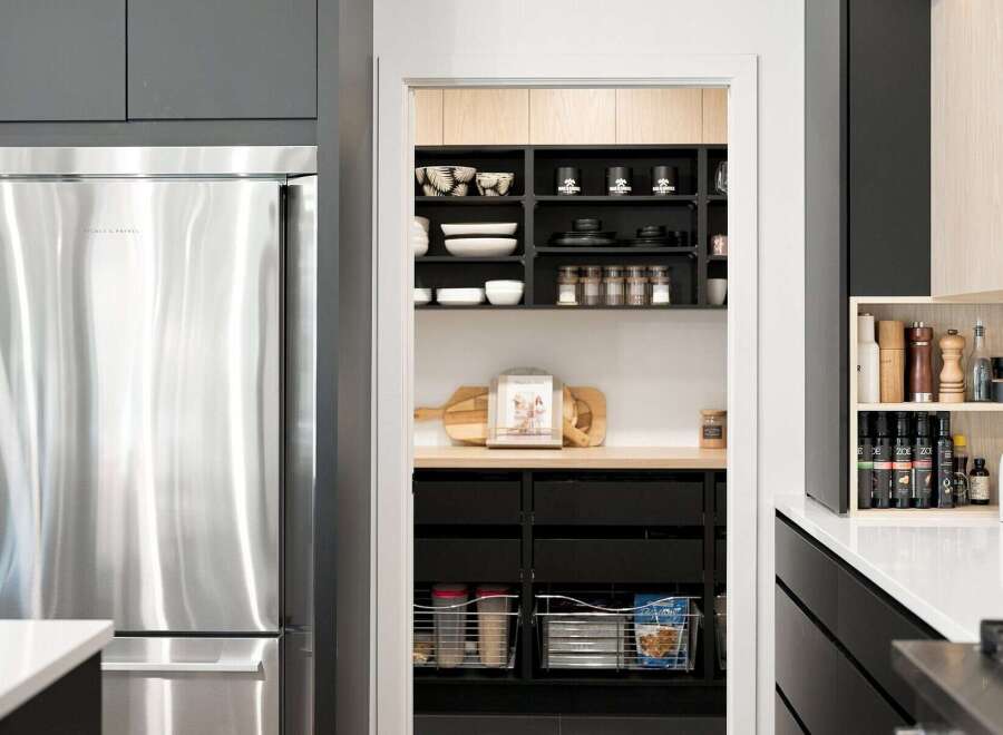 This modern kitchen boasts a sleek stainless steel refrigerator and a well-organized pantry with ample shelving for all your culinary needs.