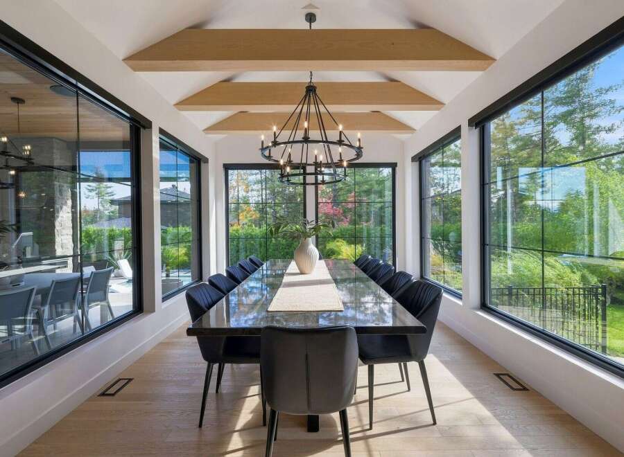 Experience luxurious dining in this elegant space, featuring a long, polished dark wood table surrounded by plush black chairs.