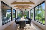 Experience luxurious dining in this elegant space, featuring a long, polished dark wood table surrounded by plush black chairs.