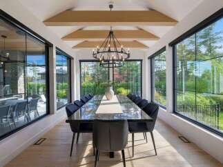 Experience luxurious dining in this elegant space, featuring a long, polished dark wood table surrounded by plush black chairs.