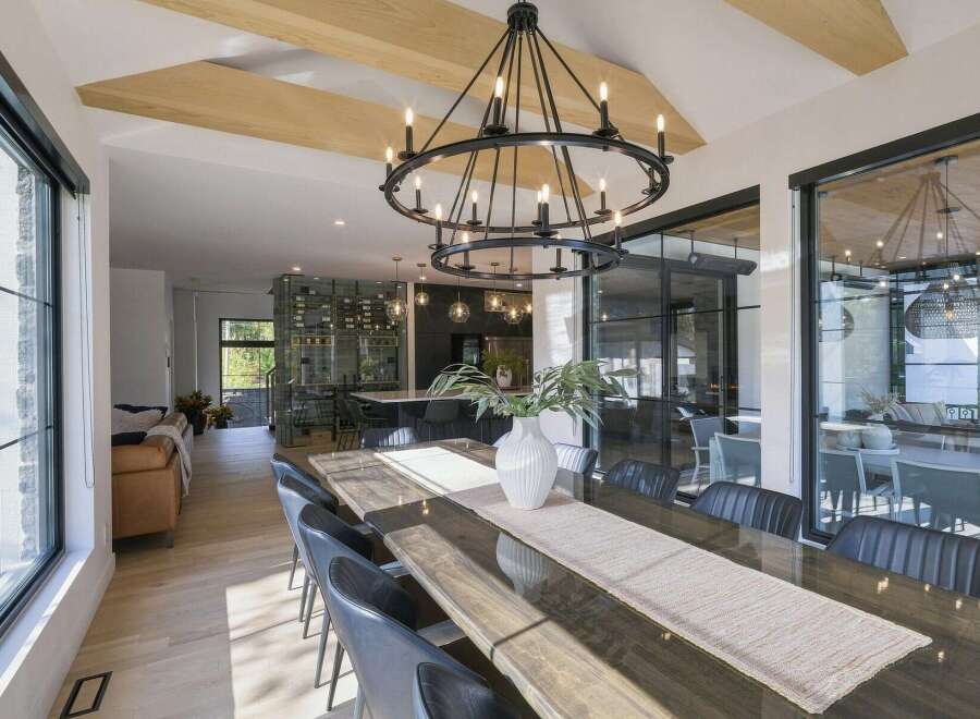 Experience modern luxury in this spacious dining area, featuring a stunning double-ring chandelier and exposed wooden beams that add architectural interest.