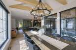 Experience modern luxury in this spacious dining area, featuring a stunning double-ring chandelier and exposed wooden beams that add architectural interest.