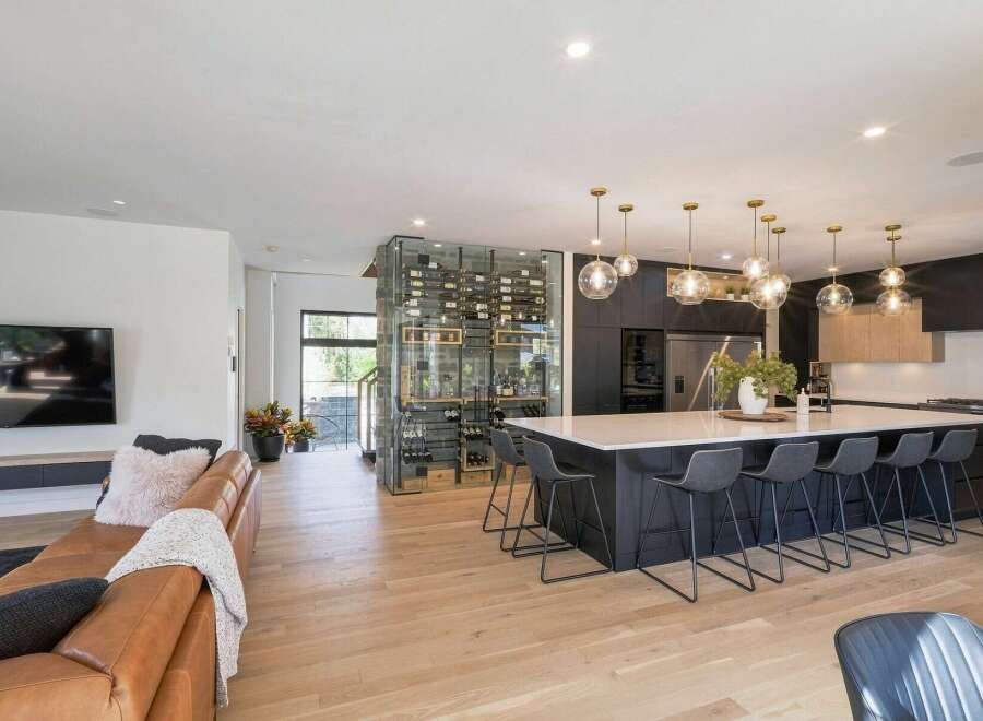 Experience luxury living in this modern open-concept home, featuring a stunning glass-encased wine cellar that serves as a sophisticated focal point.