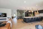 Experience luxury living in this modern open-concept home, featuring a stunning glass-encased wine cellar that serves as a sophisticated focal point.