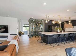 Experience luxury living in this modern open-concept home, featuring a stunning glass-encased wine cellar that serves as a sophisticated focal point.