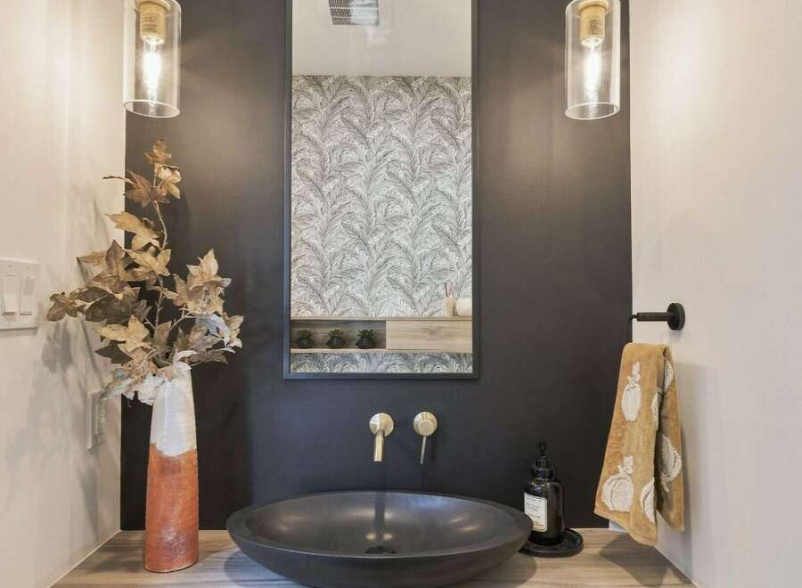 This modern bathroom features a sleek, dark vessel sink paired with elegant brass faucets.