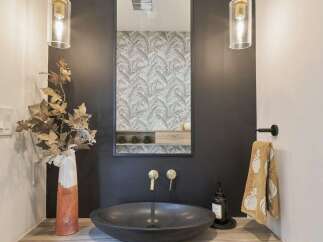 This modern bathroom features a sleek, dark vessel sink paired with elegant brass faucets.