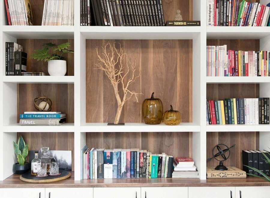 This beautifully organized bookshelf features a variety of books, decorative items, and plants, creating a warm and inviting atmosphere.