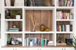 This beautifully organized bookshelf features a variety of books, decorative items, and plants, creating a warm and inviting atmosphere.
