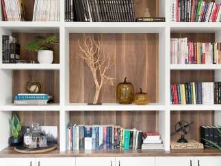 This beautifully organized bookshelf features a variety of books, decorative items, and plants, creating a warm and inviting atmosphere.