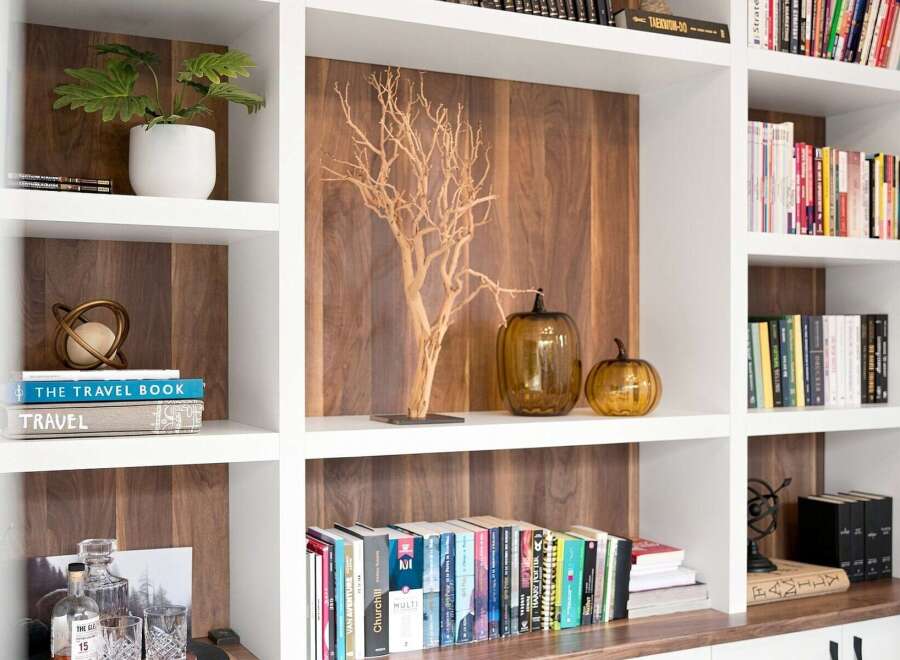 This built-in bookshelf features a modern aesthetic with warm wood paneling and crisp white shelving.