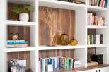 This built-in bookshelf features a modern aesthetic with warm wood paneling and crisp white shelving.