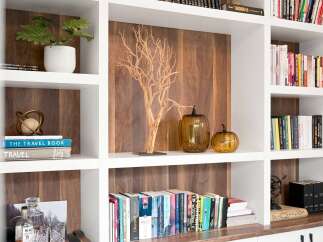 This built-in bookshelf features a modern aesthetic with warm wood paneling and crisp white shelving.
