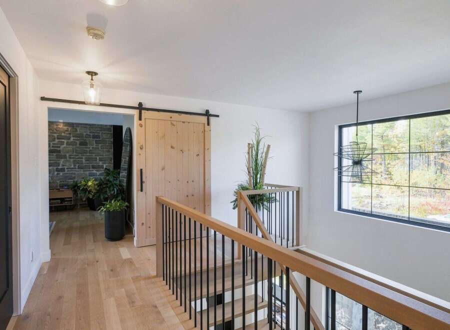 This modern hallway features a light wood floor and a striking wooden barn door, adding rustic charm.
