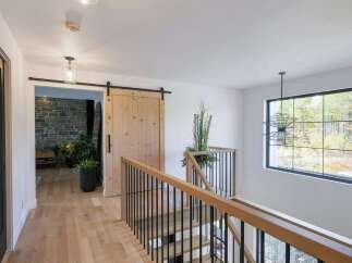 This modern hallway features a light wood floor and a striking wooden barn door, adding rustic charm.