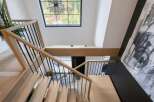 Ascend this stunning modern staircase featuring light wood treads and sleek black metal railings.
