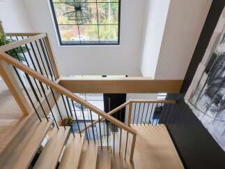 Ascend this stunning modern staircase featuring light wood treads and sleek black metal railings.