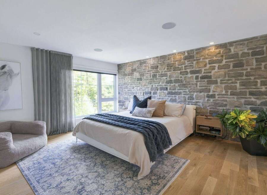 Experience rustic charm in this inviting bedroom, featuring a striking stone accent wall that adds warmth and texture.