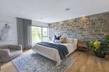 Experience rustic charm in this inviting bedroom, featuring a striking stone accent wall that adds warmth and texture.