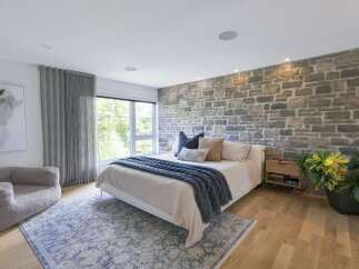 Experience rustic charm in this inviting bedroom, featuring a striking stone accent wall that adds warmth and texture.