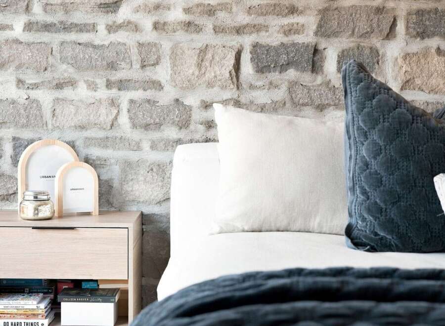 Experience rustic charm with this bedroom featuring a striking stone accent wall, creating a warm and inviting atmosphere.