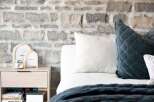 Experience rustic charm with this bedroom featuring a striking stone accent wall, creating a warm and inviting atmosphere.