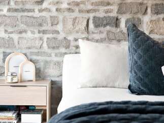 Experience rustic charm with this bedroom featuring a striking stone accent wall, creating a warm and inviting atmosphere.