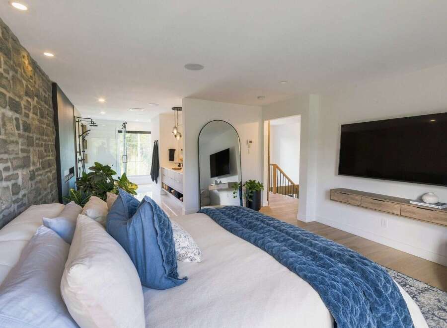 Experience luxury living in this master suite, featuring a stunning stone accent wall and an open-concept bathroom with a walk-in shower.