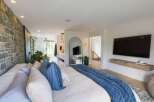 Experience luxury living in this master suite, featuring a stunning stone accent wall and an open-concept bathroom with a walk-in shower.