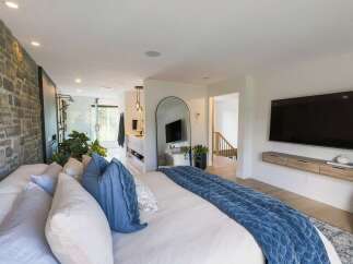 Experience luxury living in this master suite, featuring a stunning stone accent wall and an open-concept bathroom with a walk-in shower.