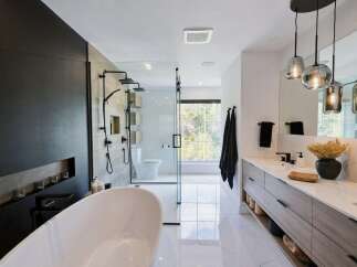 Experience modern luxury in this stunning bathroom, featuring a freestanding soaking tub and a spacious glass-enclosed shower with multiple showerheads.