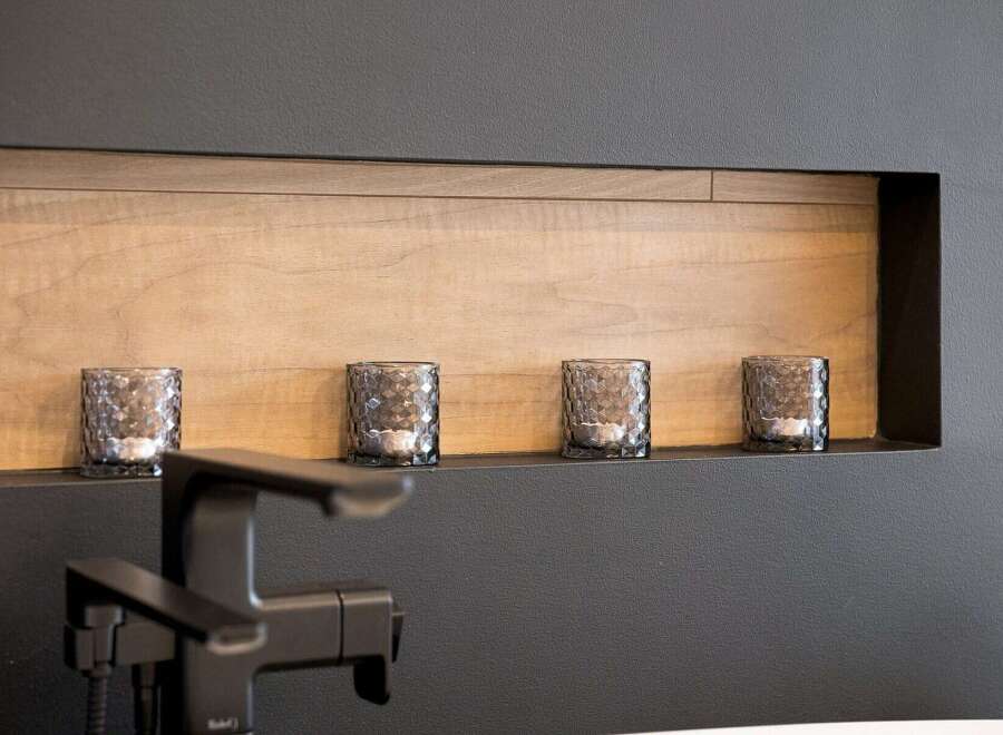 Enhance your bathroom's ambiance with this modern recessed shelf, featuring a warm wood-paneled interior and a sleek black finish.