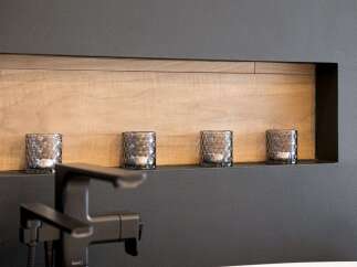 Enhance your bathroom's ambiance with this modern recessed shelf, featuring a warm wood-paneled interior and a sleek black finish.