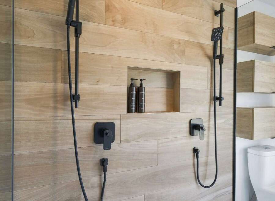 Experience modern luxury in this bathroom featuring a sleek, dual-shower system with black fixtures.