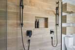 Experience modern luxury in this bathroom featuring a sleek, dual-shower system with black fixtures.