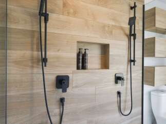 Experience modern luxury in this bathroom featuring a sleek, dual-shower system with black fixtures.