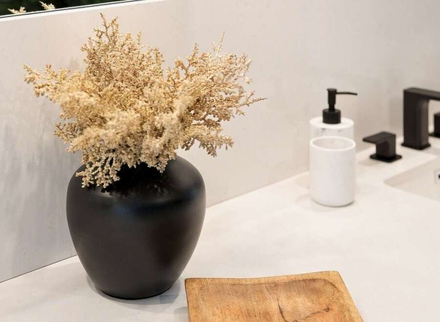 Elevate your bathroom's aesthetic with this modern vanity featuring a sleek black vase filled with dried floral accents.