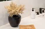 Elevate your bathroom's aesthetic with this modern vanity featuring a sleek black vase filled with dried floral accents.