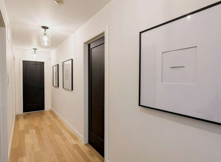 Step into this elegant hallway featuring sleek black doors and a warm, inviting hardwood floor.