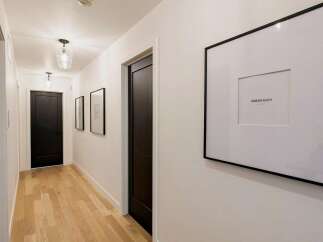 Step into this elegant hallway featuring sleek black doors and a warm, inviting hardwood floor.