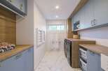 This modern laundry room boasts a stylish and functional design, featuring light blue cabinetry with elegant gold hardware.
