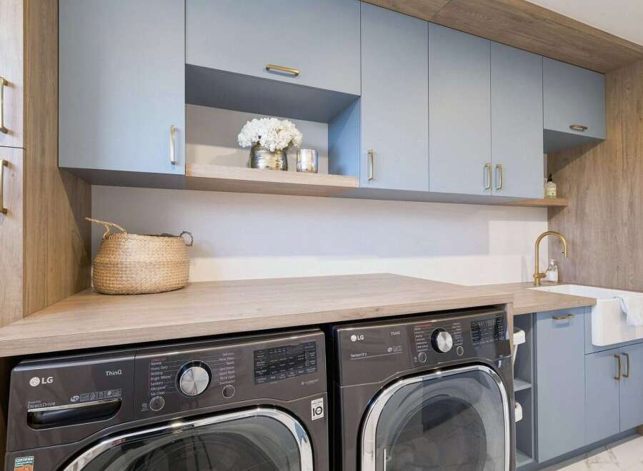 This modern laundry room boasts a sleek design with light blue cabinetry and warm wood accents.
