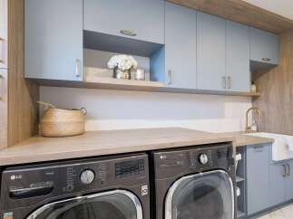 This modern laundry room boasts a sleek design with light blue cabinetry and warm wood accents.