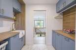 This modern laundry room boasts a stylish design with light blue cabinetry and warm wood accents.